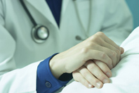 Physician hand holding patient hand