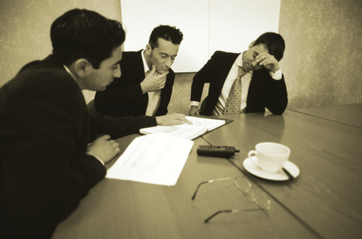 Image of an three men reviewing documentation to make a decision